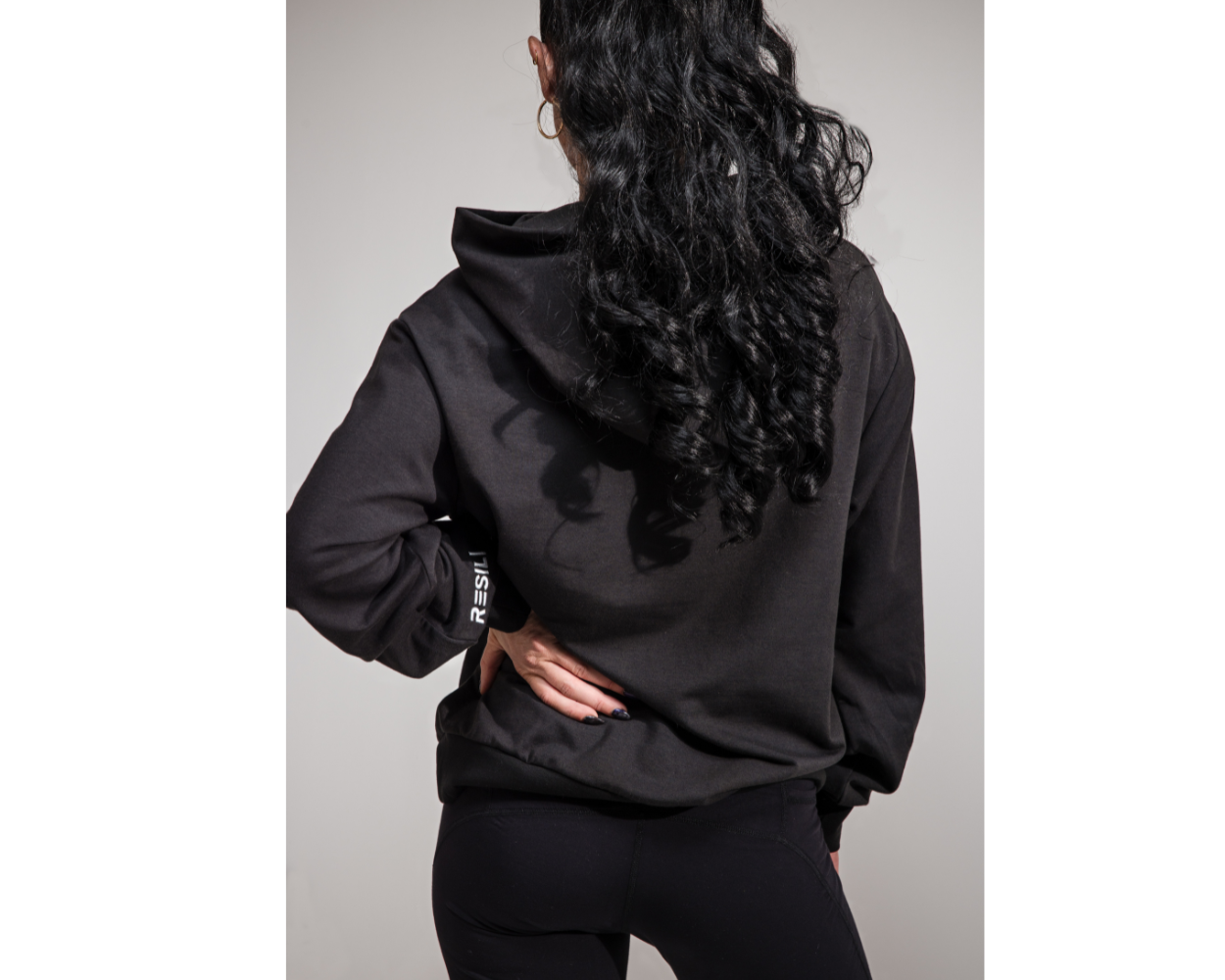 Person wearing a black hoodie and pants on a plain background