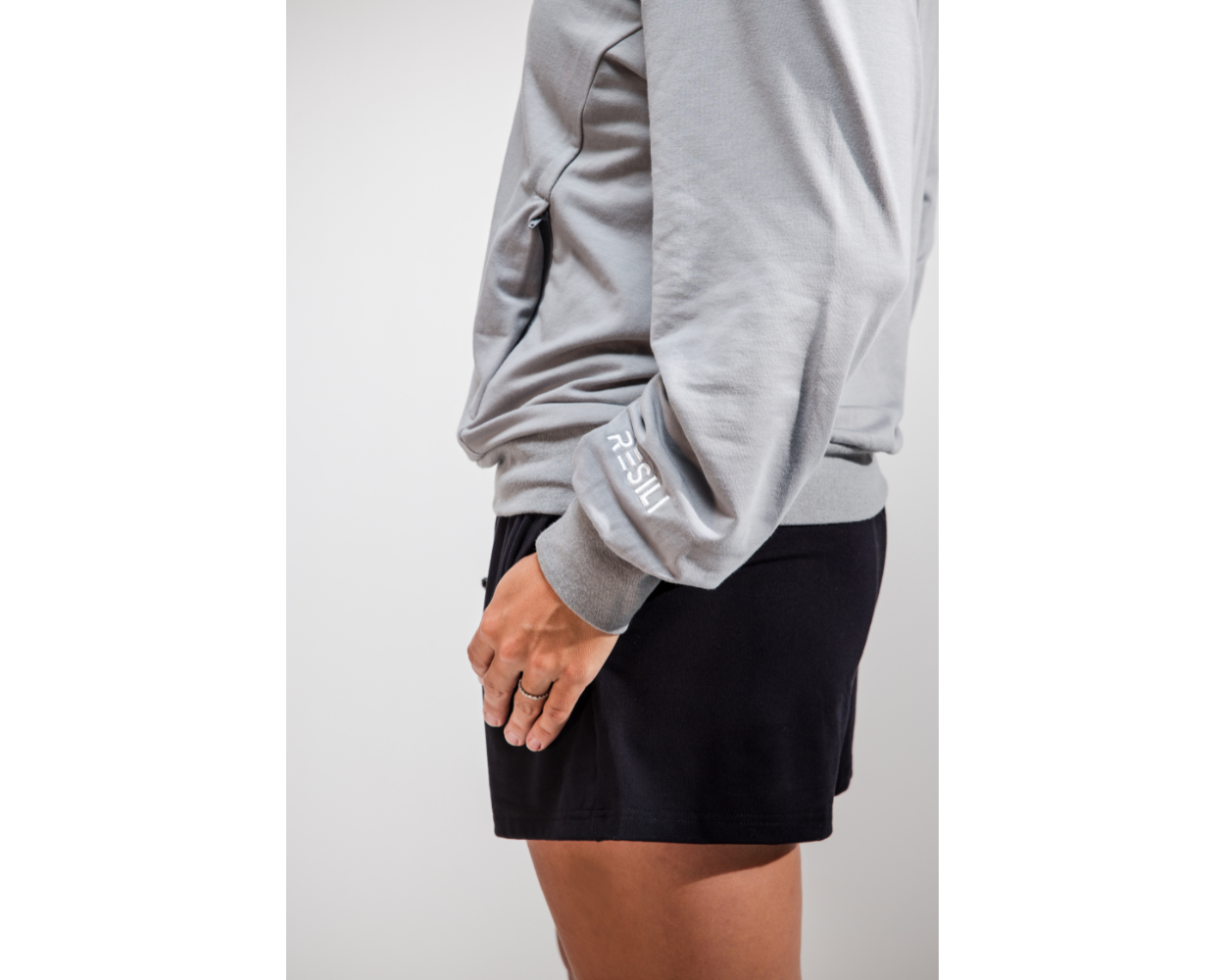 Person wearing a gray sweatshirt and black shorts on a white background