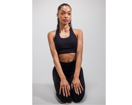 Woman in black athletic wear sitting on a white background