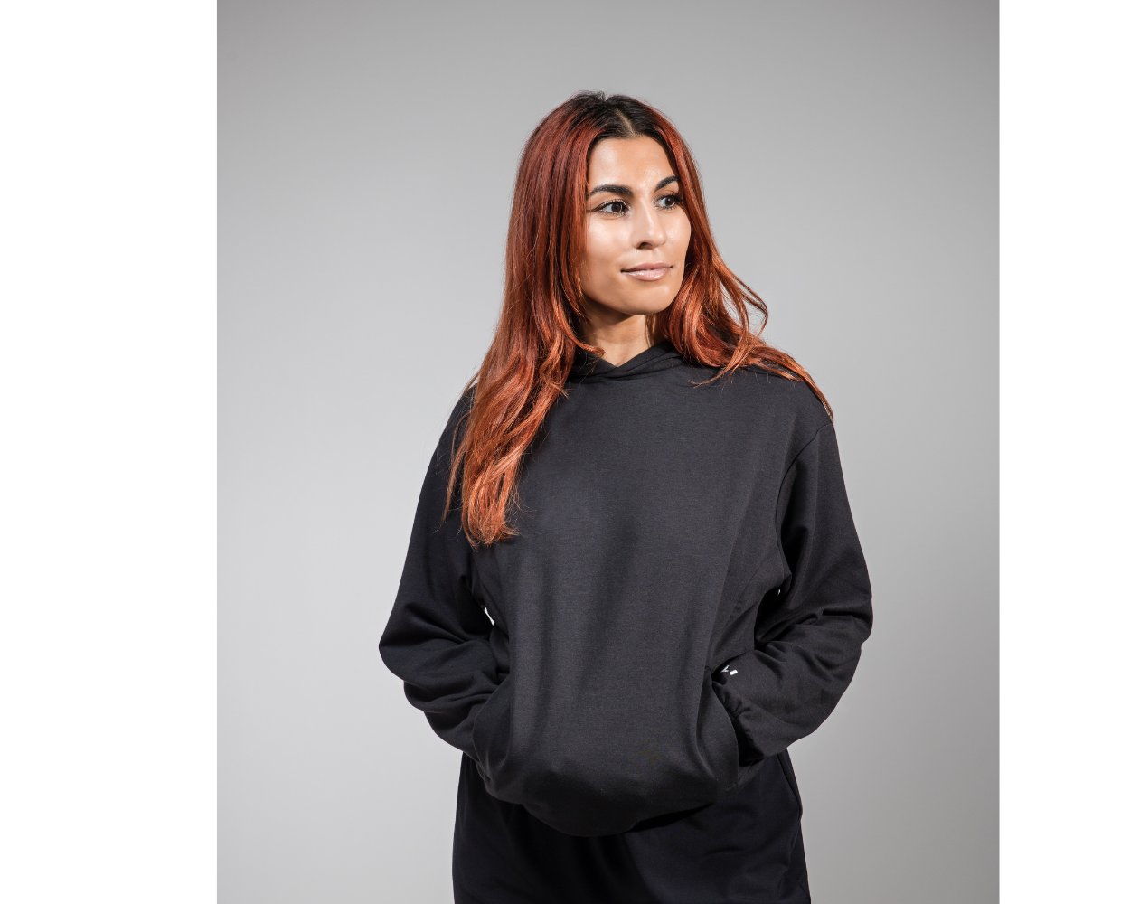 Person wearing a black hoodie on a gray background