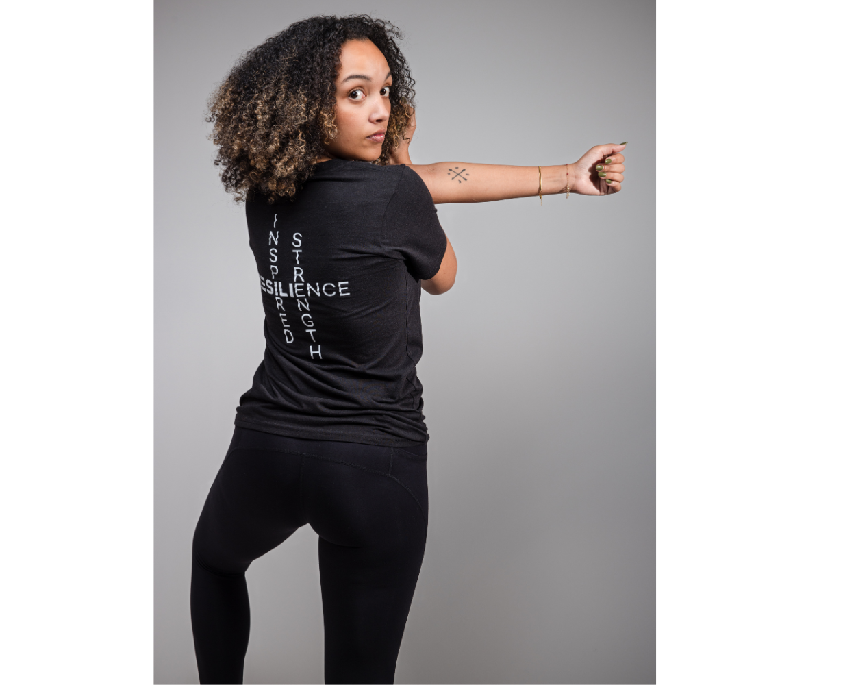 Person wearing a black t-shirt with text, standing against a gray background