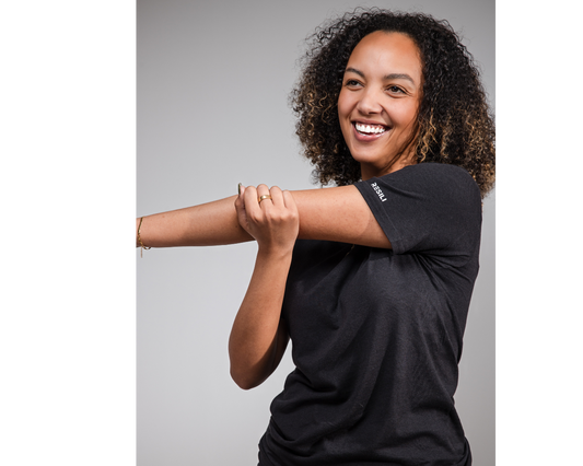Woman wearing a black t-shirt with a brand logo on a gray background