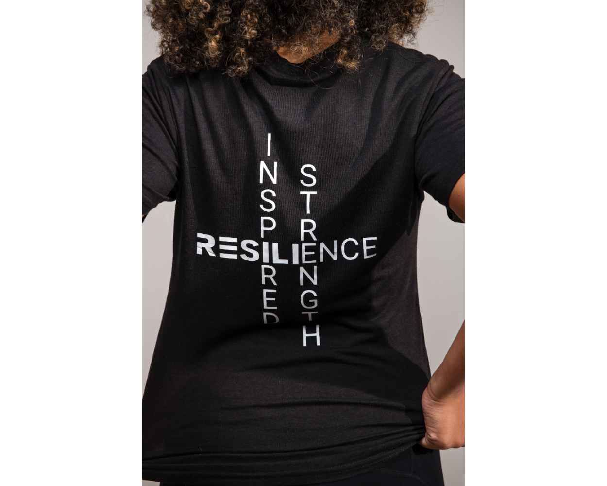 Person wearing a black t-shirt with motivational text on a plain background