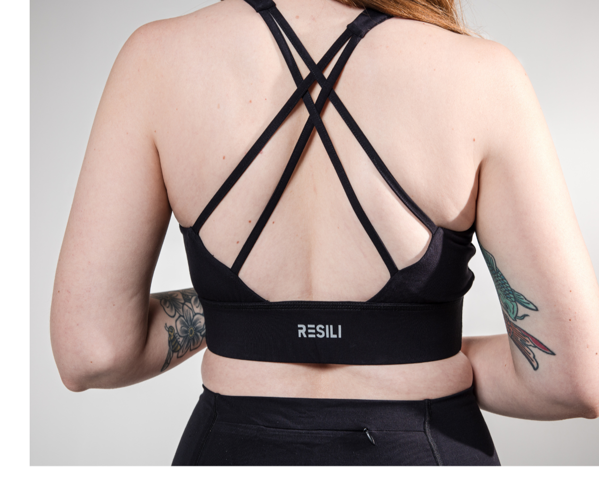 Person wearing a black sports bra with 'RESILI' branding on a gray background