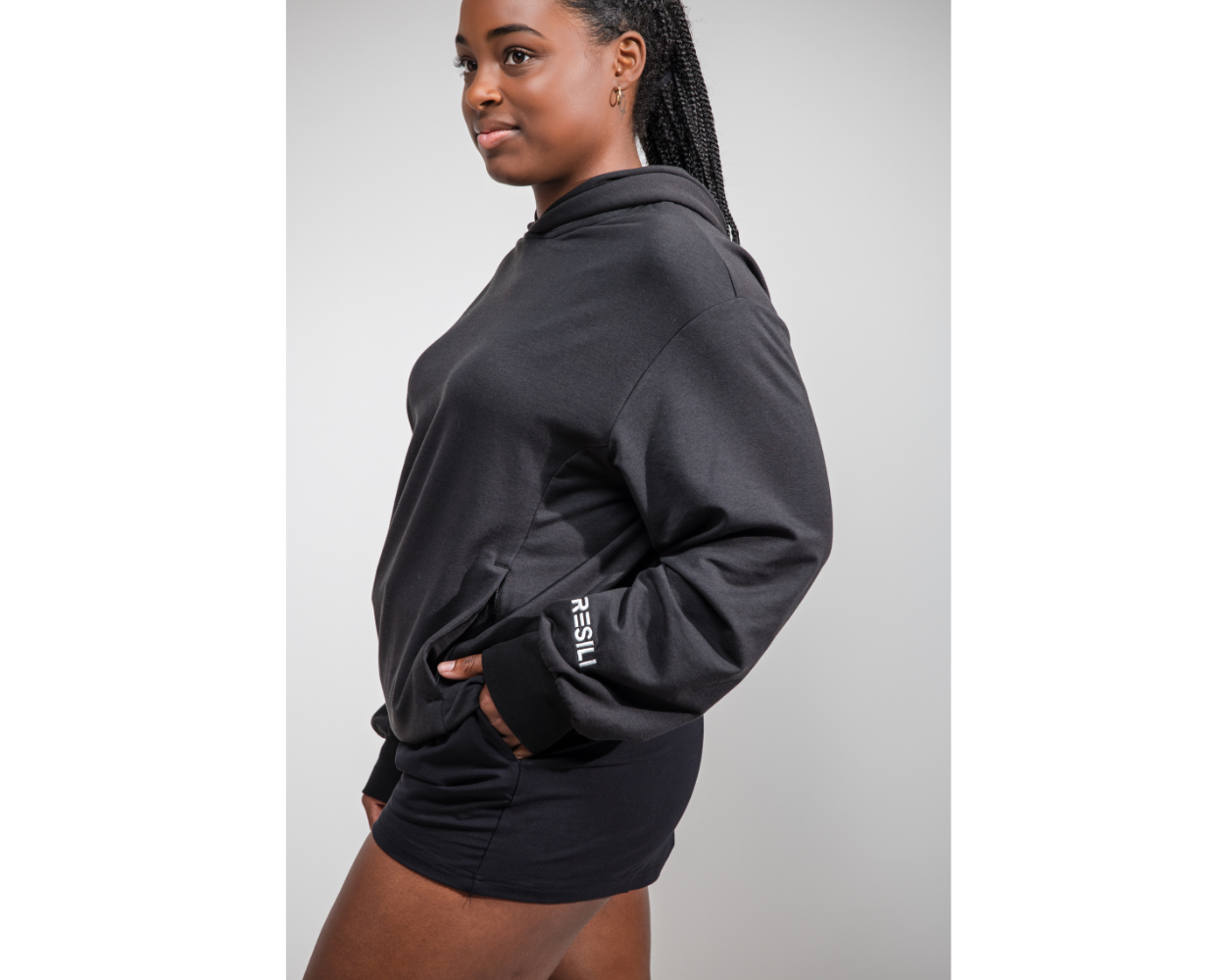 Person wearing a black hoodie with a visible brand logo on a plain background