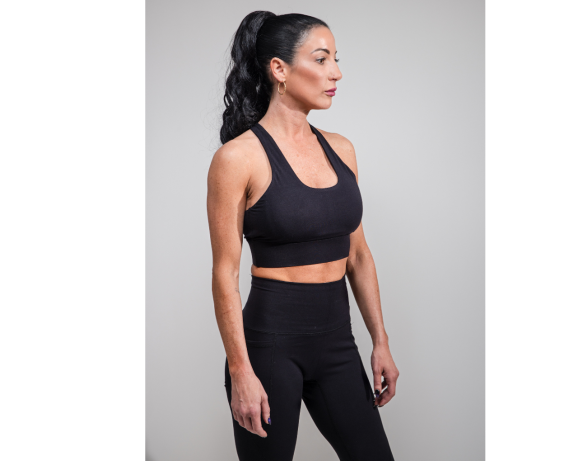 Woman wearing a black sports bra and leggings on a gray background