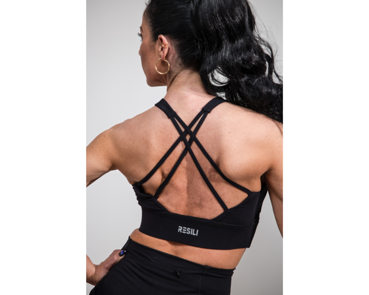 Person wearing a black sports bra with 'RESILI' branding on a gray background