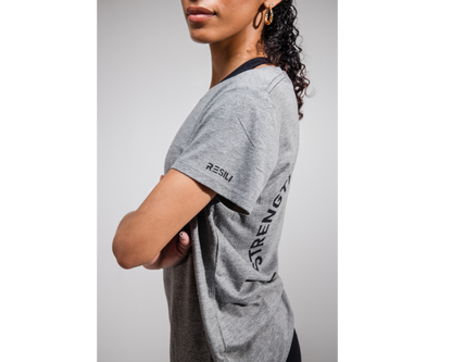 Person wearing a gray t-shirt with text on a plain background