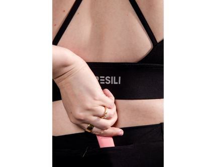 Person wearing a black sports bra with 'PESILI' branding on a white background