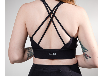 Person wearing a black sports bra with 'RESILI' branding on a gray background