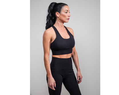 Woman wearing a black sports bra and leggings on a gray background